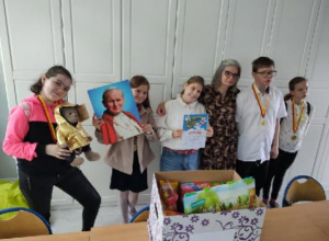 Na zdjęciu znajduje się sześć osób: pięć uczniów i nauczycielka religii. Uczniowie mają zawieszone na szyi medale. Uczennica stojąca przy oknie trzyma maskotkę - jedną z nagród, druga od lew