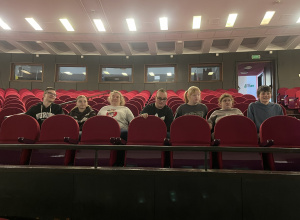 Uczniowie wcielają się w rolę widzów, siedząc w czerwonych fotelach widowni.