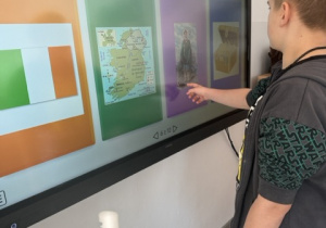 Chłopiec wybiera odpowiednią nazwę „St. Patrick” na tablicy multimedialnej podczas zajęć z okazji Dnia Świętego Patryka.